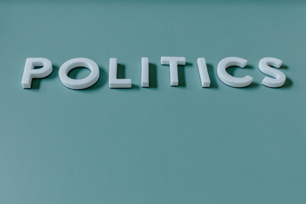When Politics Becomes Punishment: The Dangerous Culture of Vindictiveness in Ghana Close-up image of the word 'Politics' against a teal green background, highlighting political themes.