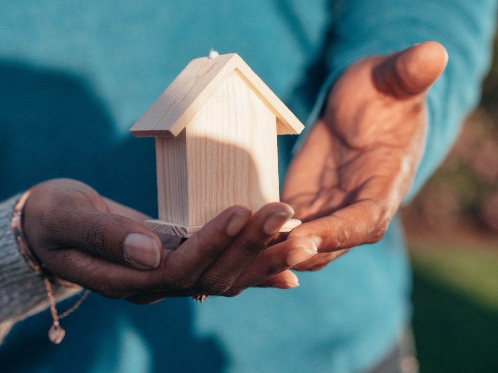 Inheritance, Succession Planning, and the Governance Challenge in Family Businesses and Founder-Led Churches Close-up of hands holding a small wooden house model outdoors, symbolizing real estate investment.